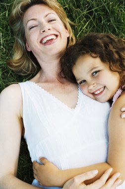 Mother and daughter lying outdoors smiling clipart