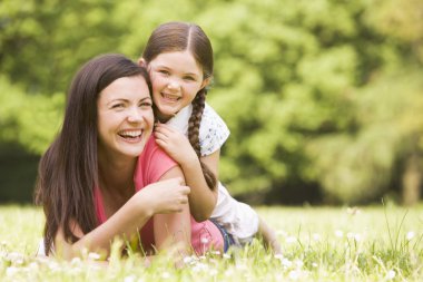 Mother and daughter lying outdoors smiling clipart