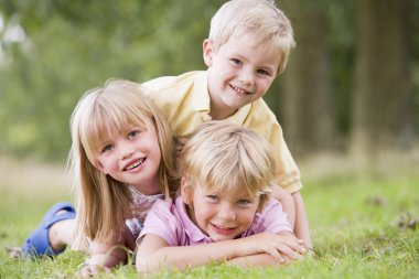 Three young children playing outdoors smiling clipart
