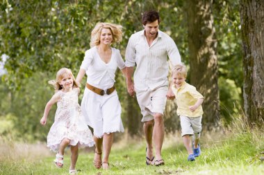 Family running on path holding hands smiling clipart