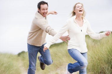 Couple running at beach smiling clipart