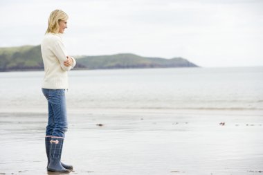 Woman standing on beach smiling clipart