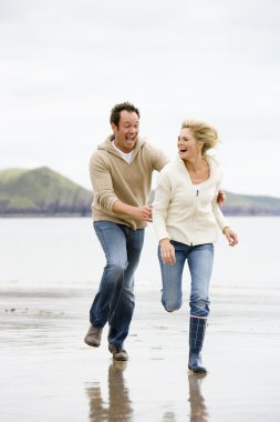 Couple running on beach smiling clipart