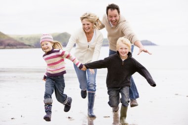 Family running on beach holding hands smiling clipart