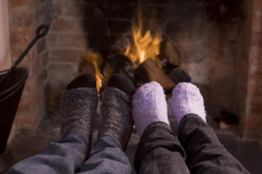 Couple's feet warming at a fireplace clipart