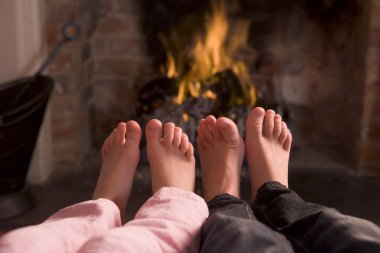 Children's feet warming at a fireplace clipart