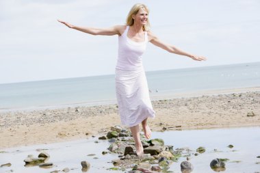 Woman walking on beach path smiling clipart