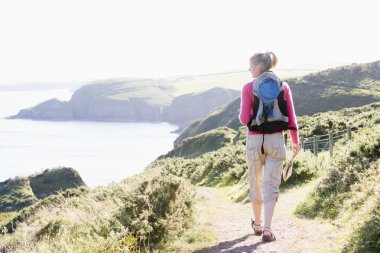 Woman walking on cliffside path clipart