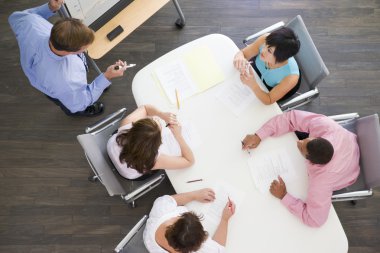 Four businesspeople at boardroom table watching presentation clipart