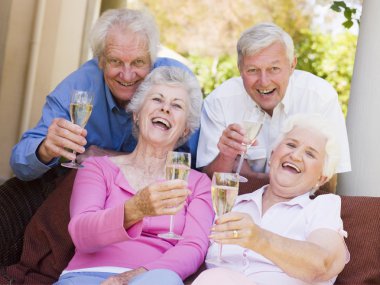 Two couples on patio drinking champagne and smiling clipart