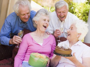 Two couples on patio with cake and gift smiling clipart