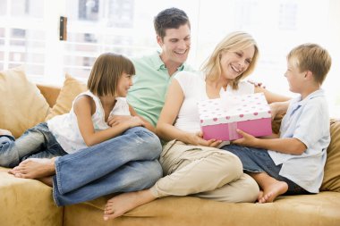 Family in living room with mother receiving gift and smiling clipart