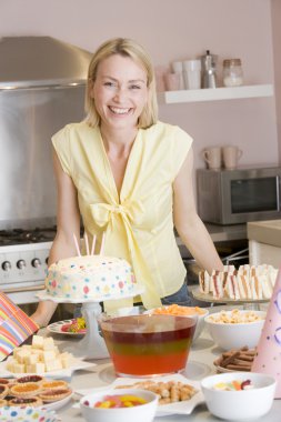 Woman at party standing by food table smiling clipart