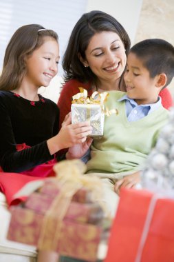 Mother Sitting With Her Son And Daughter,Exchanging Christmas Gi clipart