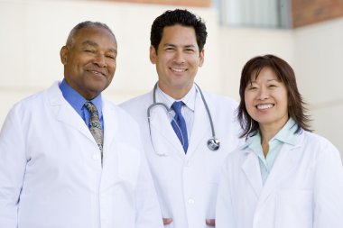 Three Doctors Standing Outside A Hospital clipart