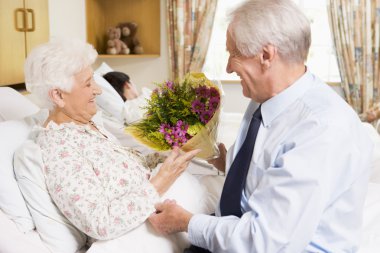 Senior Man Giving Flowers To His Wife In Hospital clipart