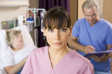 Nurse Standing In Hospital Room,Doctor Making Notes About Patien clipart