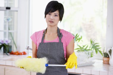 Woman Holding Duster And Wearing Rubber Gloves Not Looking Impre clipart