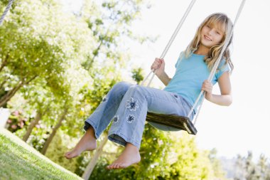 Young girl sitting on swing smiling clipart