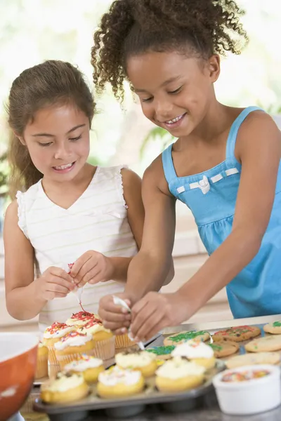Due bambini in cucina decorare biscotti sorridenti — Foto Stock