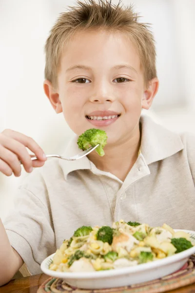 Kleiner Junge drinnen isst Pasta mit Brocolli lächelnd — Stockfoto