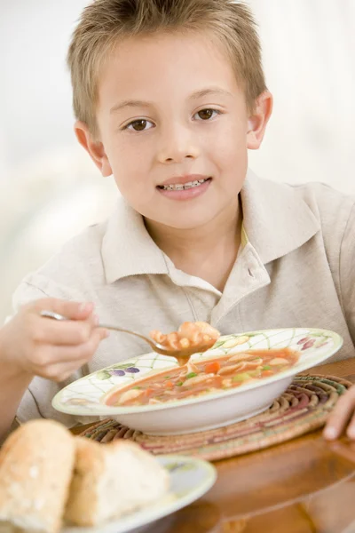 Young boy indoors eating soup — Stock Photo, Image