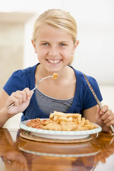 屋内で笑みを浮かべて魚 ＆ チップスを食べる若い女の子 — ストック写真