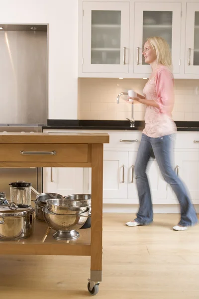 Woman walking in kitchen holding coffee — Stock Photo, Image
