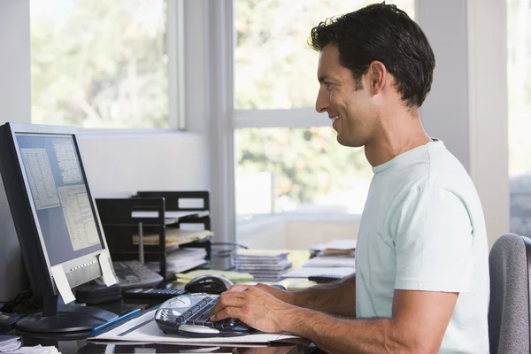 家庭办公室使用的计算机和微笑的男人 — 图库照片