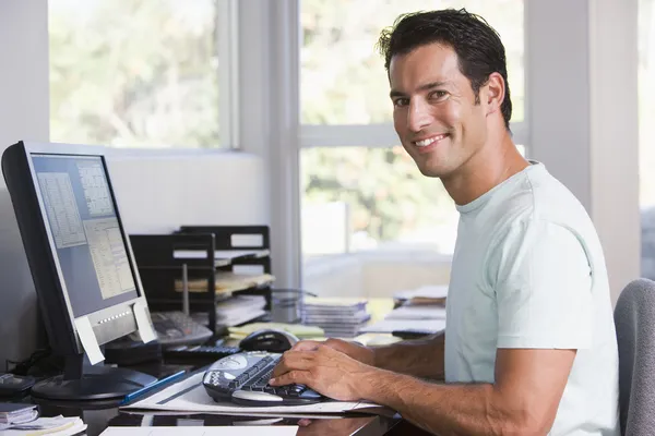 Человек в домашнем офисе с компьютером и улыбкой — стоковое фото