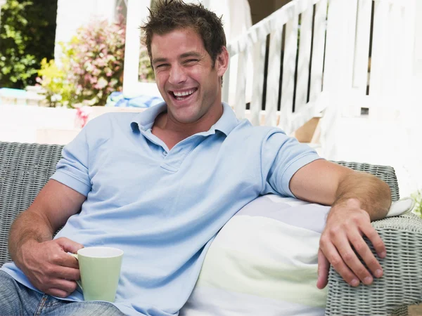 Man sitting on patio with coffee laughing — Stock Photo, Image