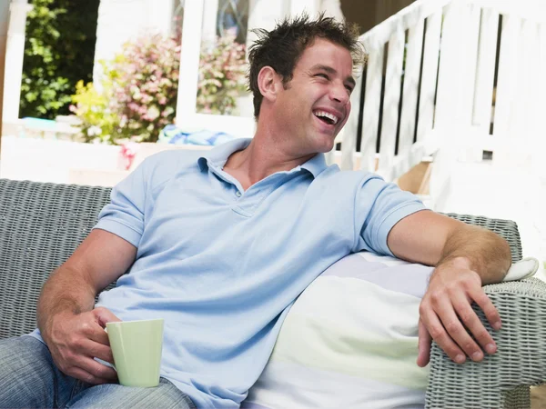 Człowiek siedzi na patio z kawy śmiejąc się — Zdjęcie stockowe