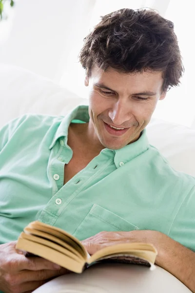 Homme lecture livre dans le salon souriant — Photo