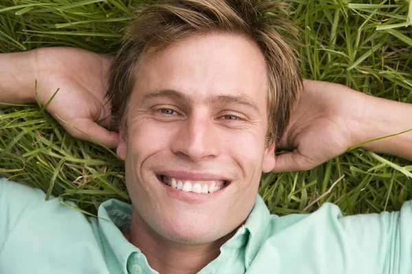 Man som ligger på gräset leende — Stockfoto
