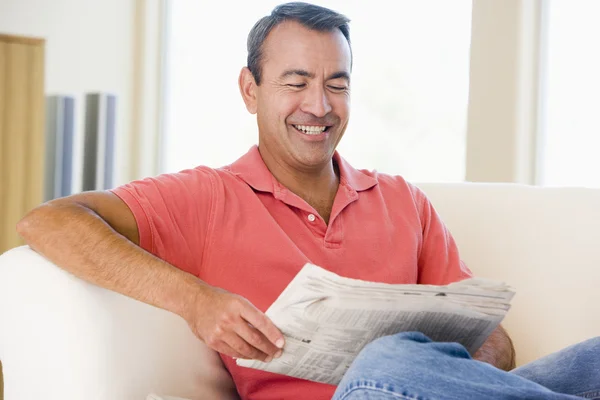 リビング ルームの笑顔で新聞を読んでいる人 — ストック写真