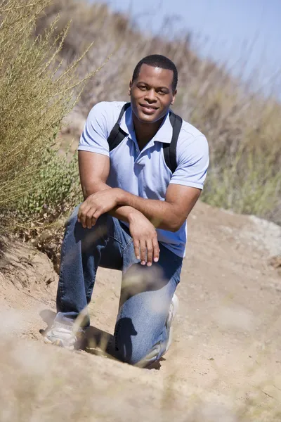 Man crouching op weg naar het strand glimlachen — Stockfoto