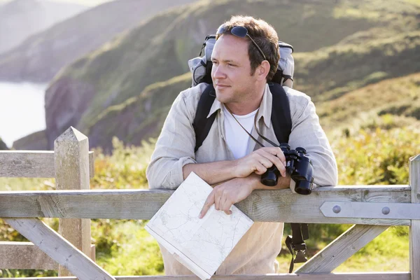 Homem relaxante no caminho da falésia segurando mapa e binóculos — Fotografia de Stock