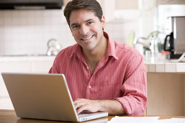 Homem na cozinha usando laptop sorrindo — Fotografia de Stock