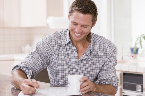Homem na cozinha lendo jornal e sorrindo — Fotografia de Stock