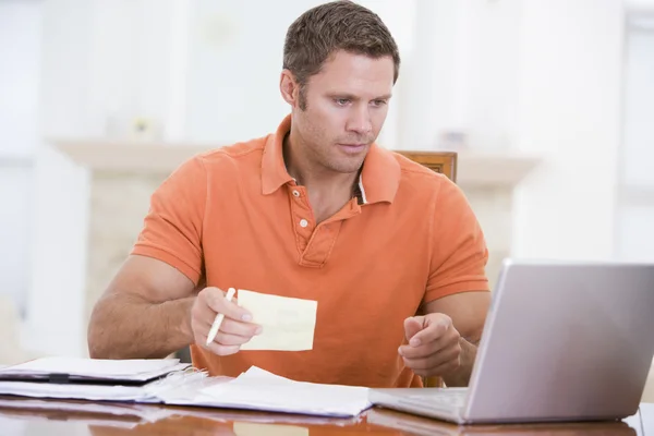 Man in de eetkamer met laptop houden papierwerk — Stockfoto