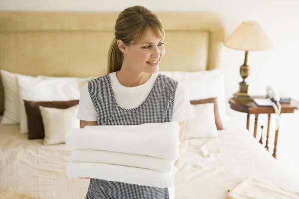 Femme de ménage tenant des serviettes dans la chambre d'hôtel souriant — Photo