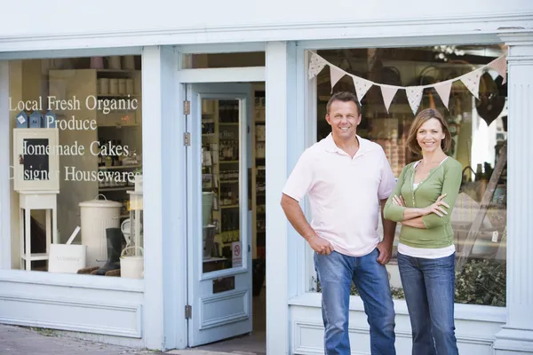 Couple standing in front of organic food store smiling — Stock Photo, Image