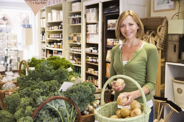 Vrouw in markt kijken naar aardappelen glimlachen — Stockfoto