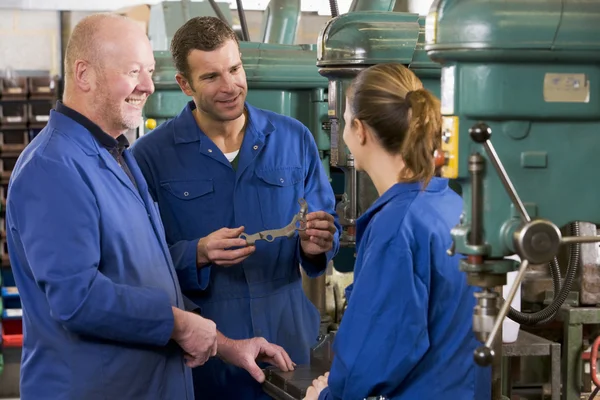Three machinists in workspace by machine talking — Stock Photo, Image