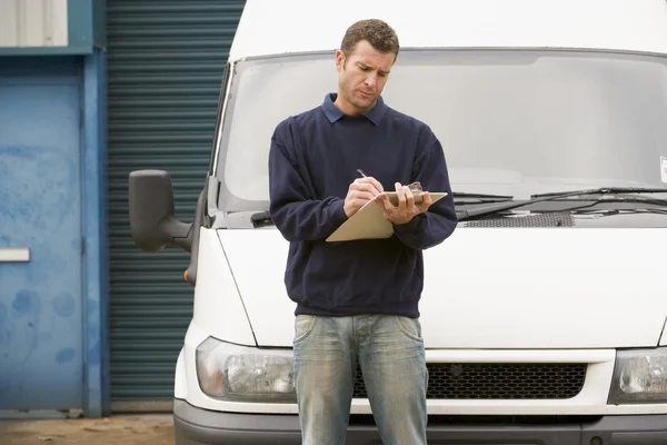 Deliveryperson stojący z van pisania w schowku — Zdjęcie stockowe