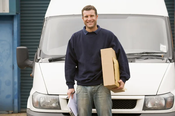 Lieferant steht mit Lieferwagen mit Klemmbrett und Schachtel lächelnd — Stockfoto