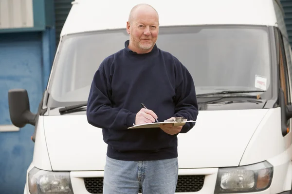 Deliveryperson standing with van writing in clipboard — Stock Photo, Image