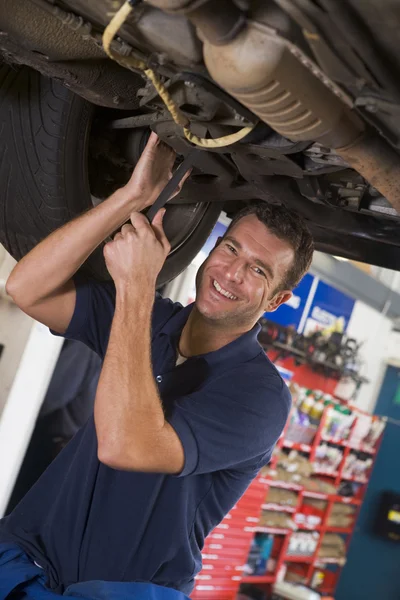 Mechaniker arbeitet unter Auto lächelnd — Stockfoto