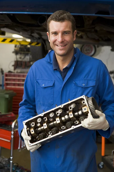 Mecánico sosteniendo parte del coche sonriendo —  Fotos de Stock