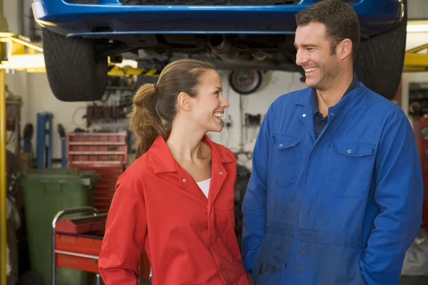 Dvě mechaniky, stojí v garáži s úsměvem — Stock fotografie